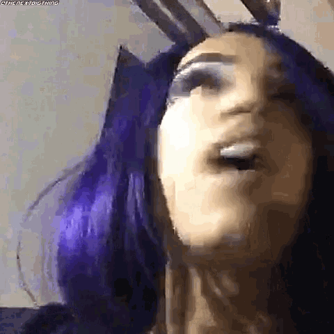 a woman with purple hair is wearing bunny ears .