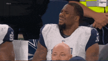 a man in a dallas cowboys uniform is sitting in the stands