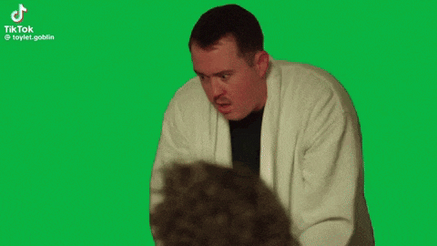 a man is holding a gun in his mouth and making a funny face on a green screen .