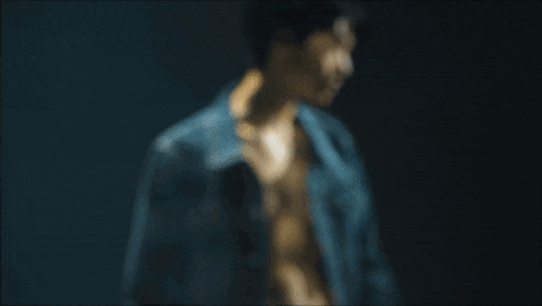 a young man in a denim jacket is looking at the camera .