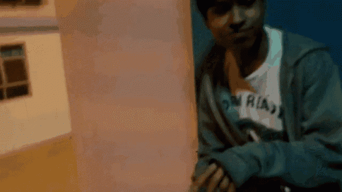 a young man wearing a gray hoodie and a white shirt with a picture of a man giving the middle finger