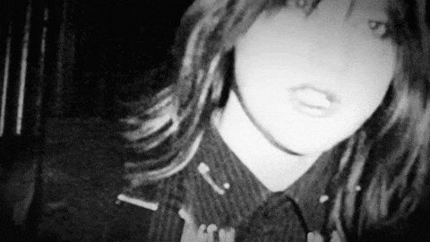 a black and white photo of a woman wearing a striped shirt and earrings .