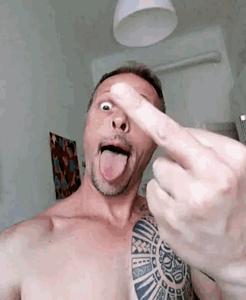 a shirtless man with a tattoo on his chest is sticking his tongue out while giving the middle finger .
