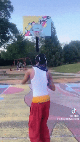 a man in a white tank top and red pants is playing basketball on a court