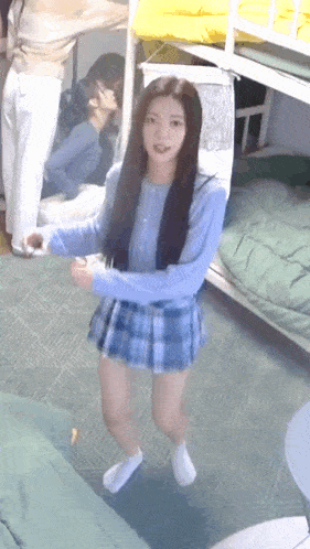 a girl in a blue plaid skirt and white socks is standing in a room with bunk beds .