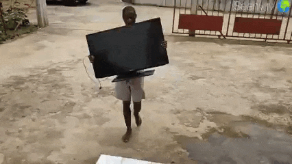 a boy is carrying a large flat screen tv in his hands