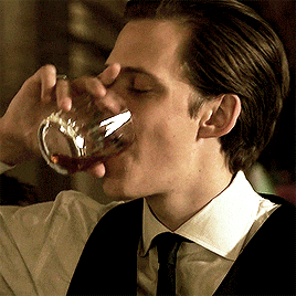 a man in a suit is drinking from a glass with his eyes closed