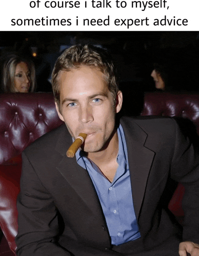 a man in a suit is smoking a cigar with a caption that says " of course i talk to myself
