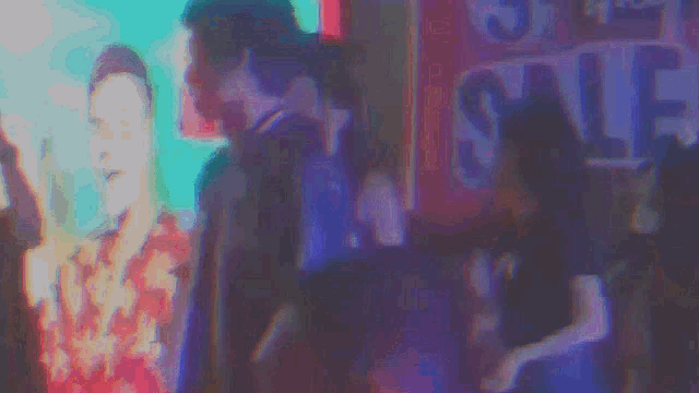 a blurry picture of a group of people dancing in front of a sign that says sale .