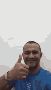 a man in a blue shirt giving a thumbs up sign