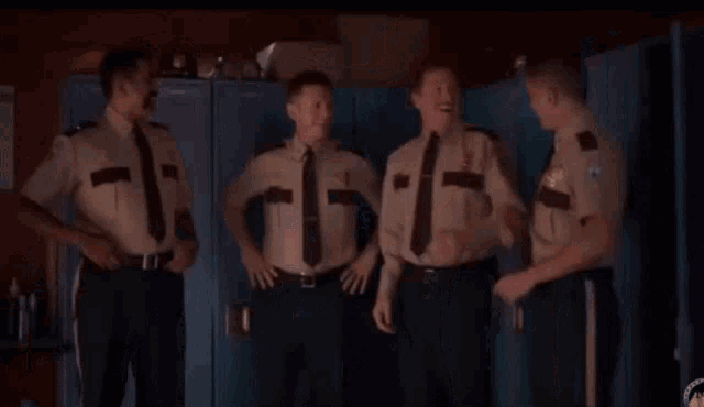 four police officers are standing in a locker room talking to each other