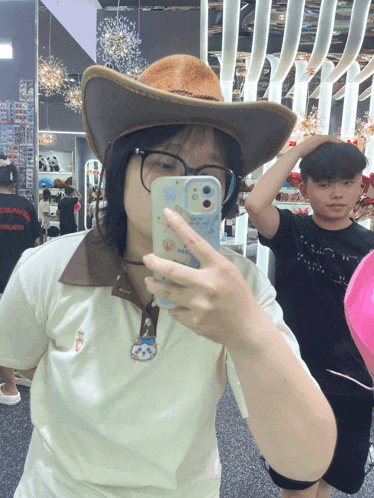 a girl wearing a cowboy hat is taking a selfie