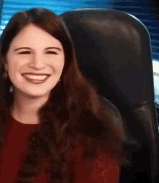 a woman is sitting in a chair laughing with her eyes closed .