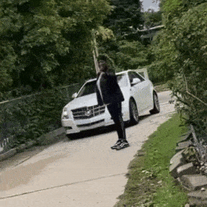 a man is standing in front of a white car on a sidewalk .