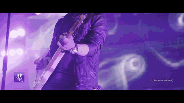 a man is playing a guitar in front of a purple background that says planetshakers.net