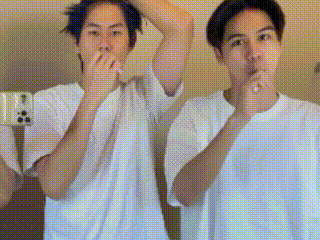 two men in white shirts are brushing their teeth in front of a mirror