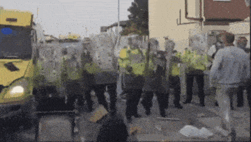 a group of police officers are standing in front of a yellow truck