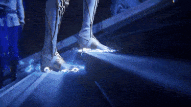 a person 's feet are glowing in the dark with a blue light behind them