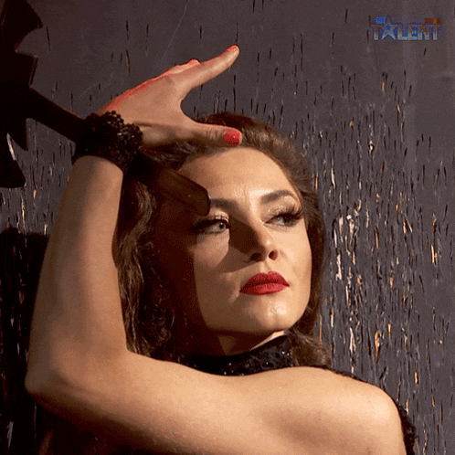 a woman with red lipstick and red nails is standing in front of a wall with the word talent visible