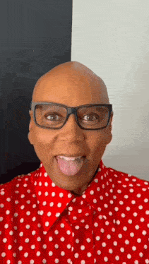 a bald man wearing glasses and a red and white polka dot shirt is sticking his tongue out .