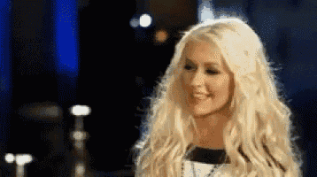 a woman with long blonde hair is smiling in a blurry photo