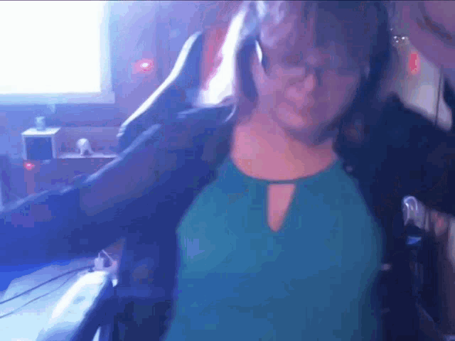 a woman in a green shirt is dancing in front of a computer monitor