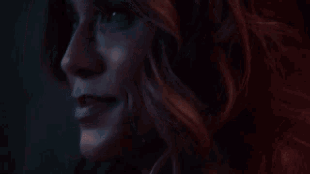a close up of a woman 's face with red hair looking at the camera .
