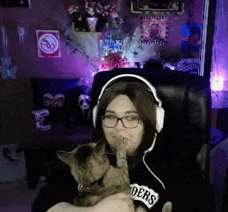 a woman wearing headphones is holding a cat that is wearing a shirt that says enders