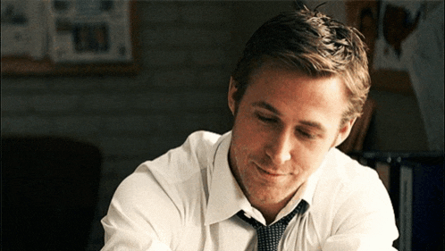 a man in a white shirt and tie looks down