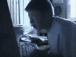 a man is typing on a keyboard in front of a computer screen