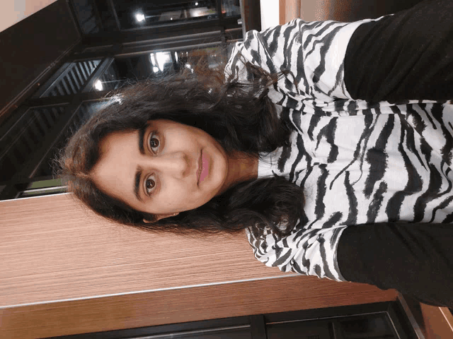 a woman wearing a zebra print shirt is smiling for the camera