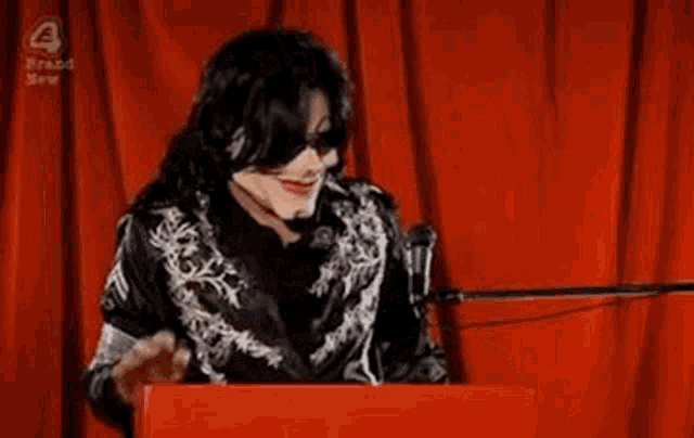 a man in a costume is standing at a podium with a microphone .