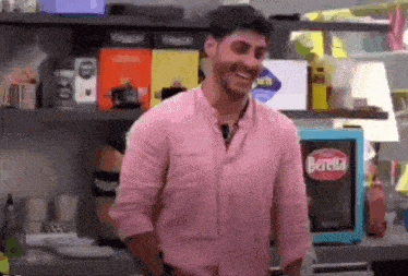a man in a pink shirt is smiling in front of a beretta refrigerator .