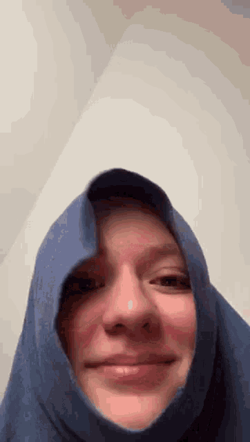 a woman wearing a blue scarf around her head is smiling .