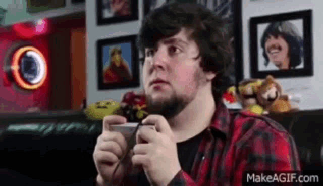 a man in a plaid shirt is playing a video game with a controller .