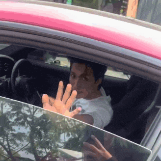 a man sitting in a car with his hand out of the window