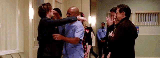 a group of people are hugging each other in a hospital hallway .