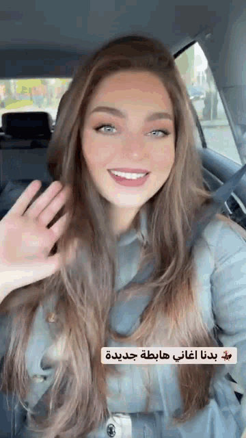 a woman is sitting in the back seat of a car and waving .