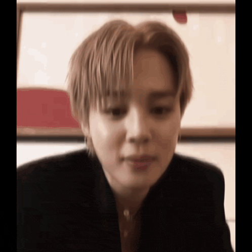 a close up of a person 's face with a blurry background and a painting in the background .