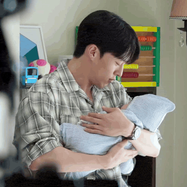 a man in a plaid shirt is holding a baby in his arms in front of an abacus