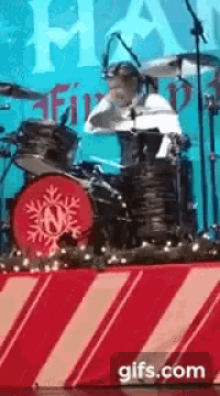 a man is playing drums on a stage with a snowflake on the drum