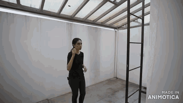 a woman stands in an empty room with the words made in animatica on the bottom right