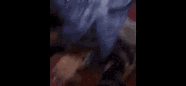 a blurry picture of a woman in a blue shirt talking to a man in a room .