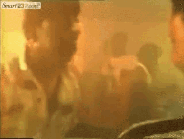 a group of people are standing in a room with smoke coming out of the ceiling .