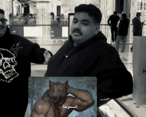 a man in a black hoodie is standing next to a picture of a wolf with muscles
