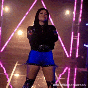 a woman in a black jacket and blue shorts is dancing on stage .