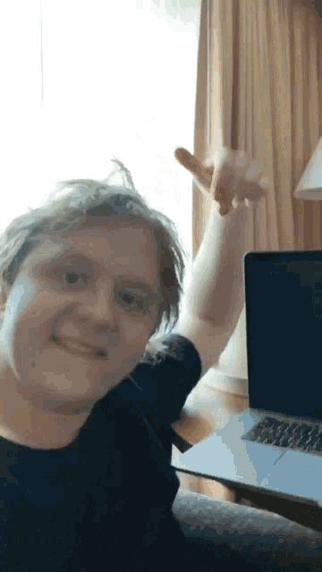 a man is sitting in front of a laptop and giving the middle finger
