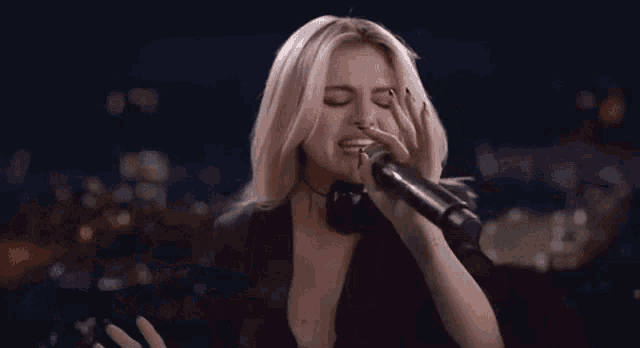 a woman is singing into a microphone while wearing a black jacket .