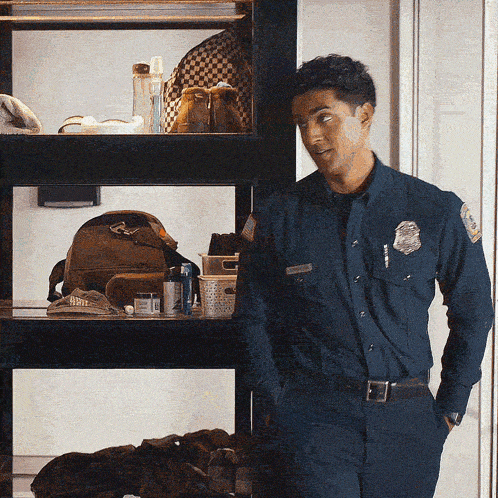 a police officer stands in front of a shelf with a backpack and a hat on it