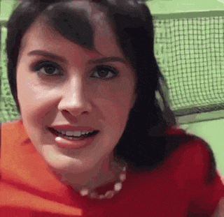 a woman in a red shirt is smiling and looking at the camera while standing in front of a tennis net .